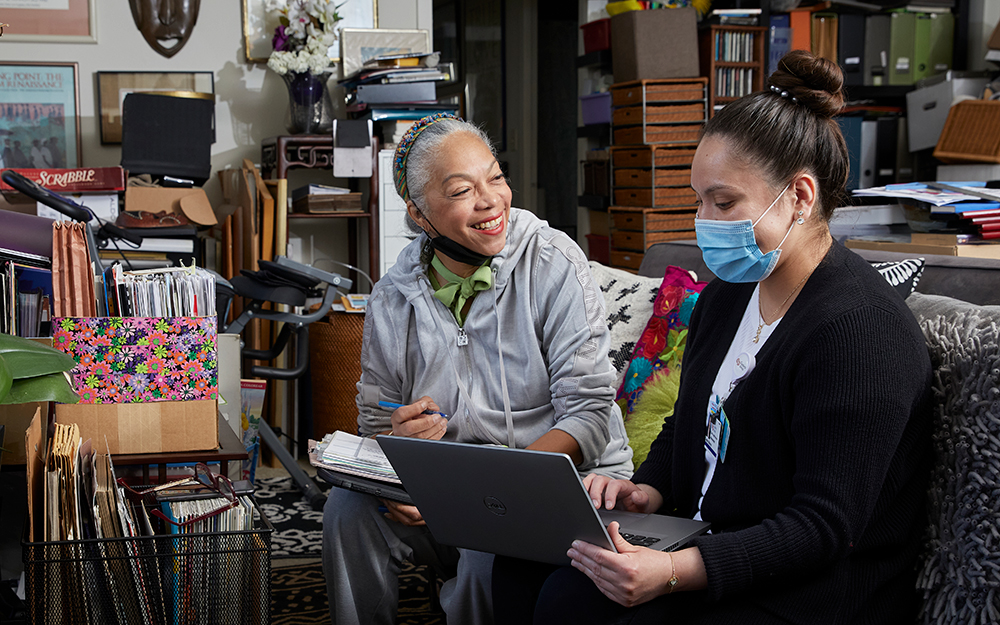 Two women in a room using a laptop.